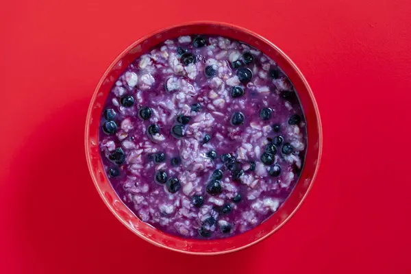燕麦粥粥 带有成熟的蓝莓 用于红色背景的健康早餐 顶部视图 免版税图库图片