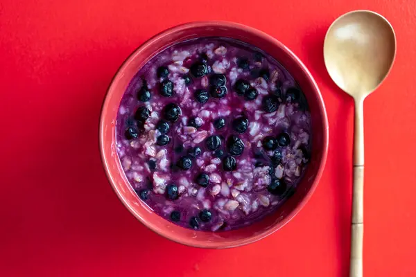 燕麦粥粥 带有成熟的蓝莓 用于红色背景的健康早餐 顶部视图 图库照片