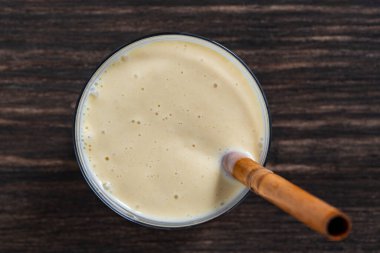 Tahta bir masada bambu pipetli muzlu mango smoothie, yakın çekim, üst manzara