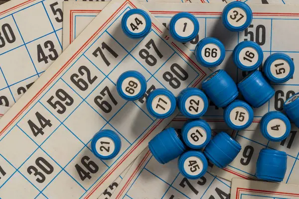 Tabletop old lotto game with cards and blue barrels on table, close up, top view