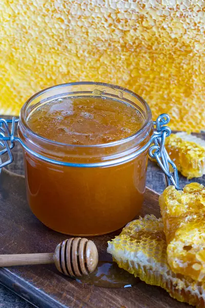 木のスプーンとハニカムが付いている厚い黄金の蜂蜜のガラス瓶 養蜂の概念について 甘い蜂蜜プロダクト 健康な食糧 ロイヤリティフリーのストック画像