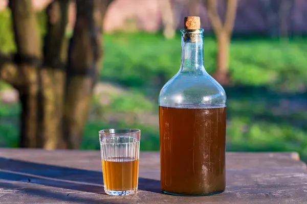 春天温暖的日子里 用发酵的桦树树液在木制桌子上做的一大瓶饮料 关门了 传统的乌克兰冷大麦在玻璃瓶中喝Kvass 在庭院中喝Glass — 图库照片