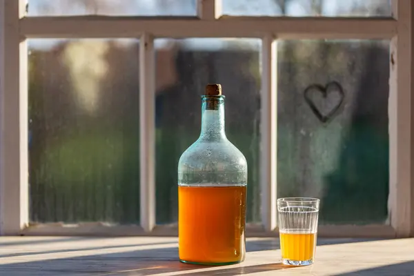 一个温暖的春日 在窗台上用发酵的桦树树液制成的大瓶子 关上了 传统的乌克兰冷大麦在玻璃瓶中喝Kvass 在庭院附近的桌子上喝玻璃杯 — 图库照片