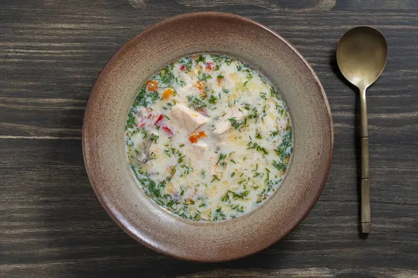 ジャガイモ ニンジン コショウ タマネギを木製のテーブルの上にセラミックプレートに入れた新鮮なクリーミーなサーモン魚のスープ おいしい夕食はサーモンの魚スープで構成されています ストック写真