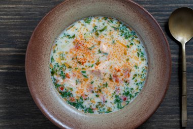 Tahta bir masada seramik tabakta patates, havuç, biber ve soğanlı taze kremalı somon balığı çorbası, yakın plan, üst manzara. Lezzetli bir akşam yemeği somonlu balık çorbasından oluşur.