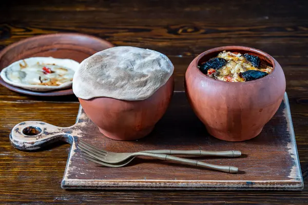 木のテーブルの上に蒸し野菜が付いている2つの粘土鍋は 閉じます 土器の蒸し食品は健康であると考えられています ロイヤリティフリーのストック写真