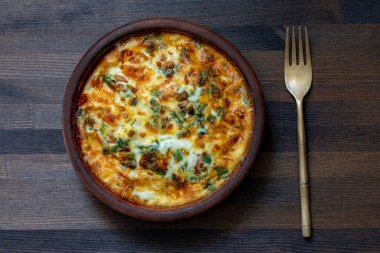 Sebzeli frittata ile seramik kase, basit yemek. Yumurtalı frittata, biber, soğan, yeşillik ve peynir ahşap masada, yakın plan, üst manzara. İtalyan omleti.