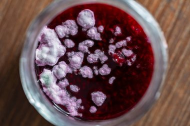 Cam bir kavanoz kırmızı ahududu reçeli içinde tehlikeli küf, yakın çekim, üst manzara. Küf sağlık için çok tehlikelidir.