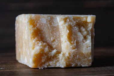 Ahşap arka planda bir parça lezzetli parmesan peyniri, yakın plan.