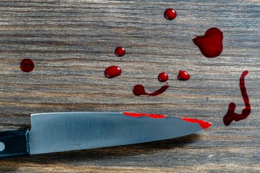 Mutfak bıçağı. Bıçağın ucunda kan var. Ahşap masada.