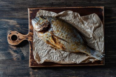 Kesme tahtasına baharat konmuş nefis fırında Dorado balığı, yakın çekim, üst manzara.