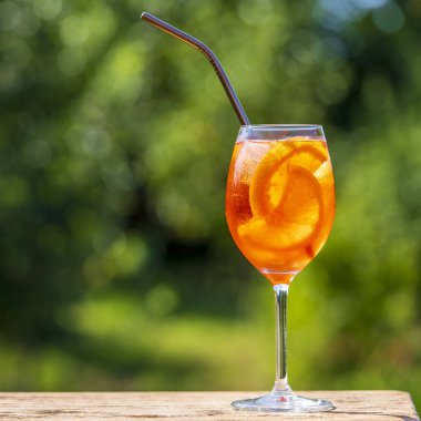 Aperol spritz kokteyli ve şarap kadehi, doğal bir arka plan. Klasik İtalyan aperatifi aperatif portakal ve buz karışımı. Yaklaş, kopyalama alanı. Yaz güneşli ferahlatıcı içecek