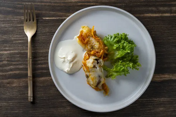 Ekşi krema ve marulla birlikte et ve pirinçle doldurulmuş iki leziz lahana rulosu.