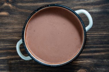 Tahta bir masada, metal bir tavada taze hazırlanmış kakao içeceği.