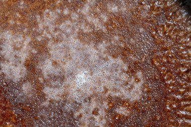 Kakao içeceğinin yüzeyinde baloncuklar, arka planda süt, yakın plan, üst manzara. Açık kahverengi kabarcıklar. Kahverengi krem köpük dokusu