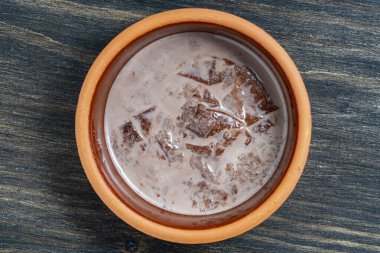 Seramik bardakta köpüklü kakao içeceği ahşap masa arkasında, yakın plan, üst manzara. Kahverengi krem köpük dokusu