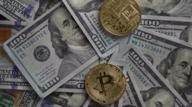 Bitcoin altın sikkeleri 100 dolarlık banknotların üzerine düşüyor, dönüyor, kapanıyor. Elektronik merkeziyetçi para konsepti. Bitcoin 'i bir dolarla değiş tokuş et. Bitcoin para ve nakit arkaplan