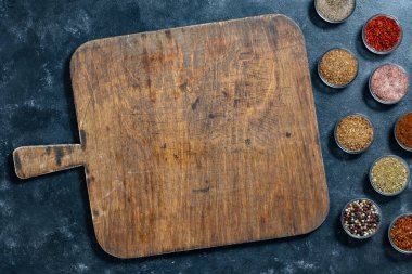 Eski ahşap kesim tahtası ve baharatlar siyah arka planda yemek pişirmek için, yakın plan, üst manzara, boşluk kopyala
