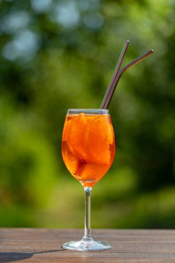 Aperol spritz kokteyli ve şarap kadehi, doğal bir arka plan. Klasik İtalyan aperatifi aperatif portakal ve buz karışımı. Yaklaş, kopyalama alanı. Yaz güneşli ferahlatıcı içecek