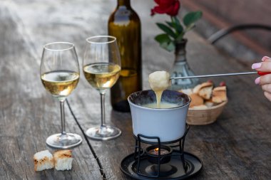 Lezzetli eritilmiş peynirli fondü, çatallar, ekmekler ve şarap ahşap masada, kapat.