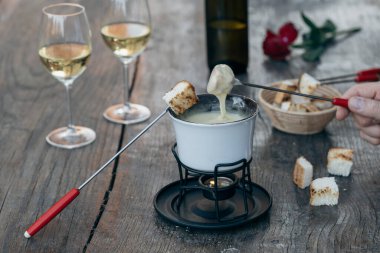 Lezzetli eritilmiş peynirli fondü, çatallar, ekmekler ve şarap ahşap masada, kapat.