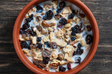 Tahta masadaki kil kasede kurutulmuş meyve, fındık, kuru üzüm, böğürtlen ve badem sütü ile tam tahıllı yulaf ezmesi. Kahvaltıda organik müsli arkaplanı