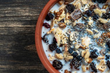 Tahta masadaki kil kasede kurutulmuş meyve, fındık, kuru üzüm, böğürtlen ve badem sütü ile tam tahıllı yulaf ezmesi. Kahvaltıda organik müsli arkaplanı