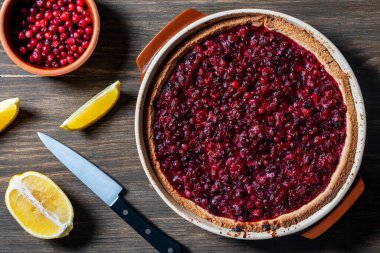 Kesilmiş limon ve bıçakla ahşap bir masada yaban mersinli kıtır hamurlu lezzetli sonbahar pastası. Yaban mersinli kek ve reçelli ve şekerli bir kabın içinde, kırsal tarzda, yakın plan, üst manzara