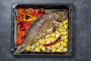 Baharatlı ve sebzeli lezzetli büyük sazan balığı. Metal bir yemek tepsisi üzerinde. Yakın çekim.