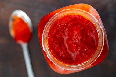 Konserve taze sebzeli cam kavanoz, siyah arka planda leço. Ev yapımı konserve yiyecekler. Doğal ev yapımı kırmızı domates ve biber sosu. Üst görünüm, kapat