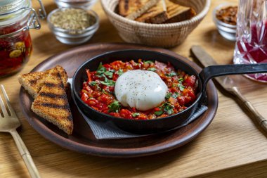 Kahvaltıda kızarmış tavada nefis shakshuka, yakın çekim. Haşlanmış yumurta, soğan, dolma biber, kırmızı domates ve yeşil maydanozdan ev yapımı shakshuka.