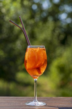 Aperol spritz kokteyli ve şarap kadehi, doğal bir arka plan. Klasik İtalyan aperatifi aperatif portakal ve buz karışımı. Kapatın. Yaz güneşli ferahlatıcı içecek