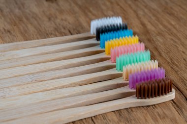 Ahşap arka planda çok renkli bambu diş fırçaları seti, yakın çekim. Sıfır atık, plastiksiz, çevre dostu organik ürün konsepti