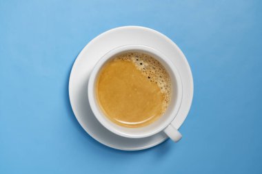 Mavi arka planda taze siyah kahve ile beyaz fincan, yakın plan, üst görünüm