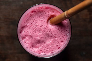 Ahşap bir masada bambu kamışlı ahududu muzlu smoothie, yakın çekim, üst manzara