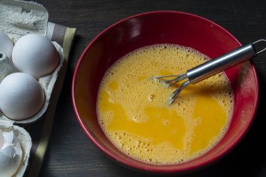 Yumurta çırpıyorum. Omlet için çırpılmış çiğ yumurta ve çırpılmış omlet. Yaklaş. Kahvaltı hazırlığı, köy tarzı.