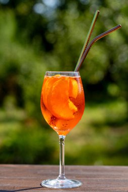 Aperol spritz kokteyli ve şarap kadehi, doğal bir arka plan. Klasik İtalyan aperatifi aperatif portakal ve buz karışımı. Kapatın. Yaz güneşli ferahlatıcı içecek