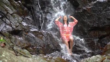 Turkuaz şelaleli genç bir kadın derin tropikal yağmur ormanlarında Koh Phangan, Tayland 'da ağır çekim.