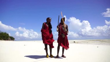 Zanzibar, Tanzanya - 12 Aralık 2019: Geleneksel kıyafetler giymiş iki Afrikalı adam okyanus kenarında, Tanzanya, Doğu Afrika 'daki Zanzibar adasının kumsalında duruyor.