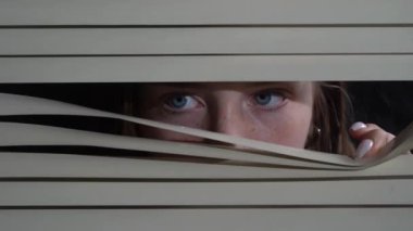 Pencereye elleriyle panjur iten genç bir kızın ön portresini kapat. Geceleri korkusuzca dışarı bakıyorum.