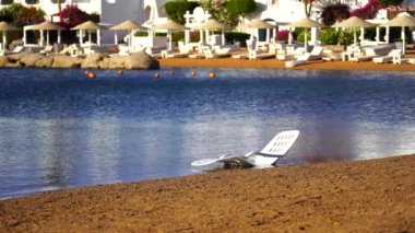 Mısır 'ın Sharm El Sheikh kentindeki tropikal bir plajda deniz suyunda beyaz plastik güneş dinleniyor. Seyahat ve doğa kavramı
