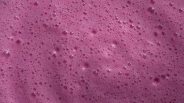 Bir bardak pembe ahududu milkshake, yakın plan, üst manzara. Taze kırmızı kızılcık, kiraz, kırmızı viburnum ya da çilekli. Baloncuklu süt smoothie yüzeyinin dokusu ve arkaplanı