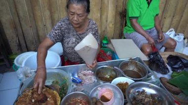 UBUD, BALI, INDONEZYA - 27 Nisan 2019: Endonezyalı fakir insanlar, Endonezya 'nın Bali adasındaki Ubud köyündeki sabah pazarında sağlıklı yiyecek satıyor ve satın alıyorlar. Sabah meyve ve sebze pazarı