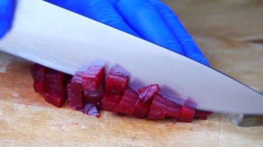 Kırmızı pancar kökünü keskin şef bıçağıyla kesmek, makro shot, pişirme işlemi, yemek için malzemeleri hazırlamak. Haşlanmış pancara yakın, sağlıklı bir yaşam tarzı.