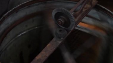 Bal sökücüdeki yuva çerçevelerinin bal peteklerinden bal özütü. Bal çerçeveleri taze organik ürün elde etmek için düzenek içinde döndürülürler. Hücrelerdeki balı döndüren elle santrifüj cihazı