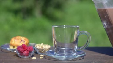 Hindistan masala çayı ya da kakaoyu, doğanın arka planında, kafenin üstündeki bir bardağa dökmek. Son moda sağlıklı içecek.