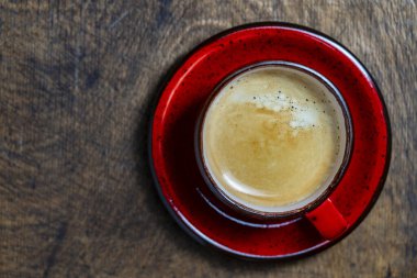 Ahşap arka planda kırmızı fincanda koyu bir kahve, üst manzara, kapatın, boşluğu kopyalayın