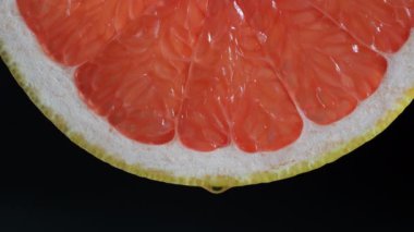 Siyah arkaplanlı sulu kırmızı greyfurt dilimi. Taze narenciye, yakın çekim, sağlıklı tatlı yiyecekler. Makro fotoğrafçılık
