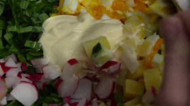 Şef, yeşil pırasa, haşlanmış yumurta, salatalık, turp, haşlanmış patates ve ekşi kremadan oluşan sağlıklı bir salata hazırlıyor. Haşlanmış yumurtalı yabani sarımsaklı salata.