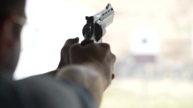Adam atış poligonundaki hedeflere tabancayla ateş ediyor. Yaklaş, bulanık odaklan. Atış talimi yaparken arkadan ateş eden bir adamın görüntüsü. Yavaş çekim